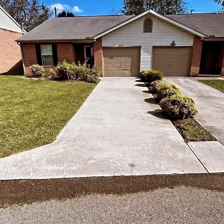 Clean concrete driveway and walk after pressure washing at a brick single-story home