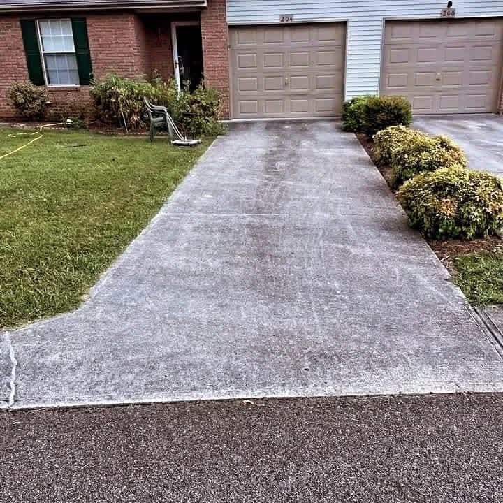 Concrete driveway washed back to an even light grey in front of a brick townhouse